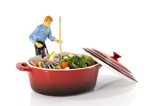 plastic model man stir vegetarian food in red saucepan