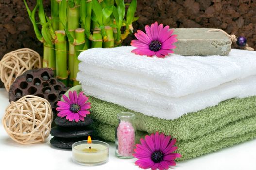 Spa scene with bamboo, towels, aromatic candles, bath salt, pebbles and daisies