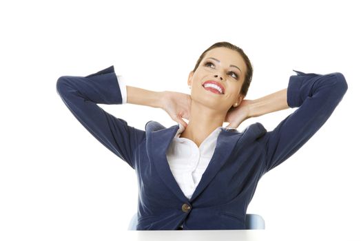 Young female executive relaxing with hands behind head
