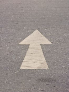 White directional arrow on asphalt pavement