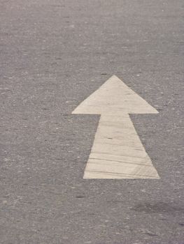 White directional arrow on asphalt pavement