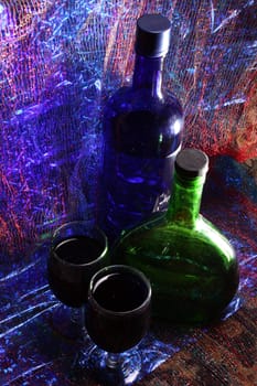 Bottles of liquor and glasses in colorful party lights.