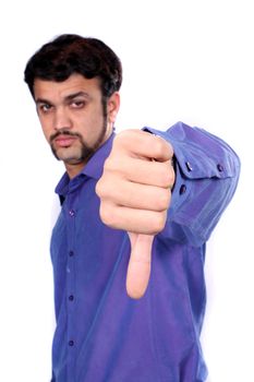 An Indian man showing the thumbs down sign meaning denial or bad luck, on white studio background. Focus on hand.