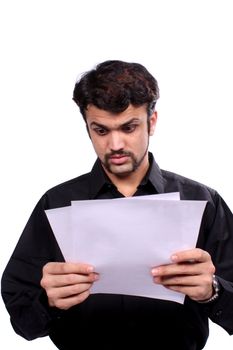 An Indian man getting shocked looking at the telephone and electricity bills, on white studio background.