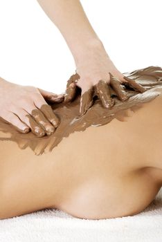 Pretty young woman relaxing being massaged in spa saloon with chocolate. Isoalted on white