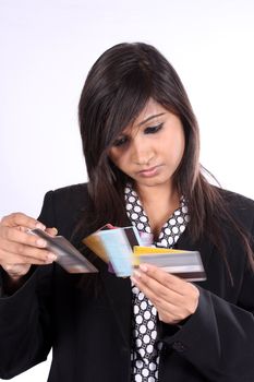 A young Indian businesswoman checking different credit cards, on white studio background.