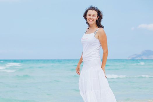 Handsome young woman walking near blue sea.