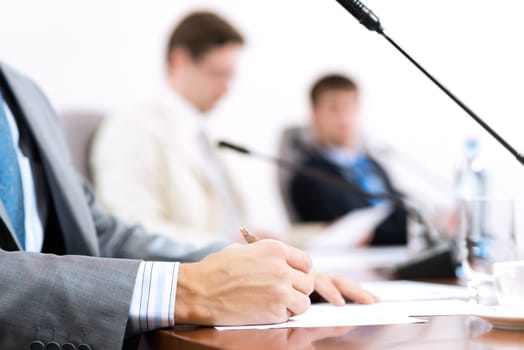 Businessman writing on paper notes, to communicate with colleagues in the background