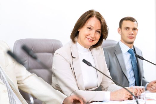 Portrait of a senior business woman at the meeting, sitting at a table on which are microphones