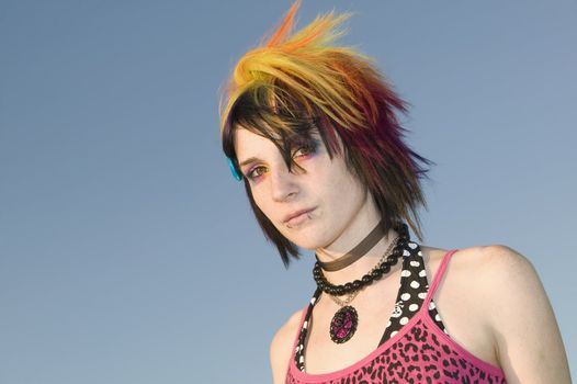 Close-up of a young punk woman against a blue sky