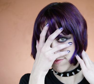 Alternative young woman with purple hair covering her face with her hand.