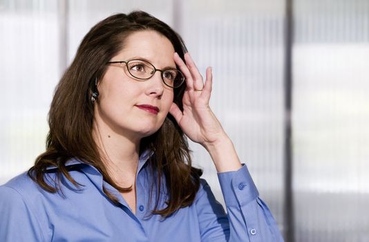 Woman in an office on a wireless phone shows mild frustration