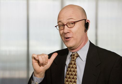 Portrait of businessman with hands-free phone in his ear making a hand gesture