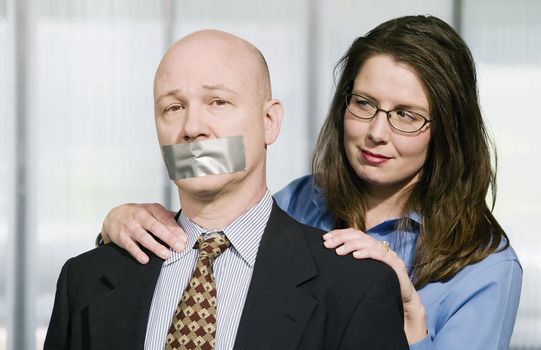 Portrait of Business team - the man is being muzzled with duct tape