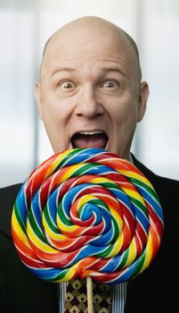 Businessman portrait with a brightly colered big lollipop