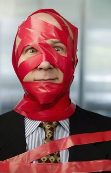 Businessman wrapped in red tape