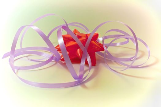 Red gift bow with lilac tapes on an abstract background