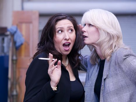 Two women engaging in gossip during a smoking break