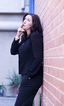 Hispanic woman in an alley smoking a cigarette