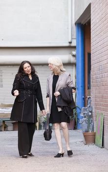 Businesswomen walking and talking in an alley