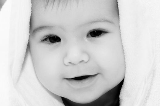 baby looking out and smiling from under blanket