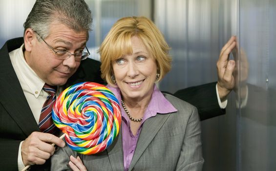 Executive in office offers coworker a big lollipop