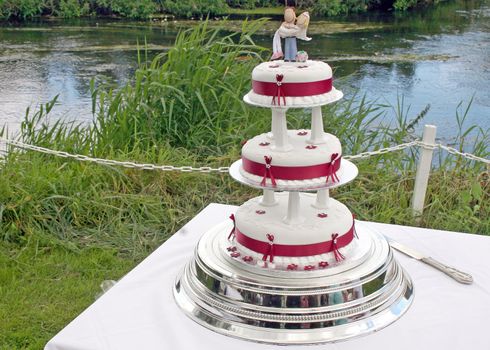 Wedding Cake with Bride and Groom and lake behind.