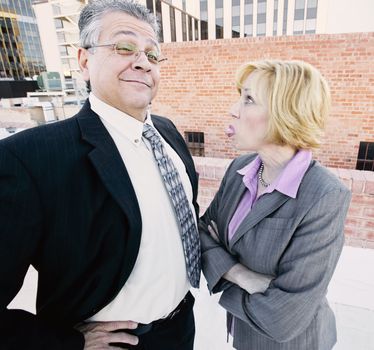 Executive woman sticks out her tongue at man on a downtown roof