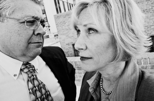 Executive man and woman on a downtown roof with ambiguous expressions