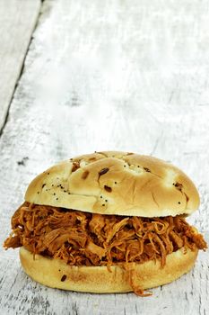 Close up of pulled chicken sandwich on a rustic background. 