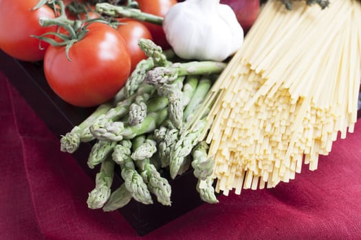 Ingredients for linguini dinner with asparagus and tomatoes.