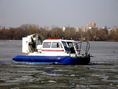 Rescue boat breaking ice on the lake at early spring