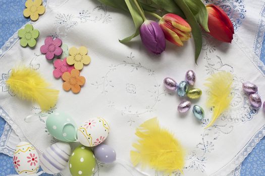 Easter goodies with chocolate eggs wrapped in foil, tulips and decorated eggs.