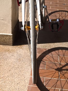 Part of bike wheel and its shadow on floor tile