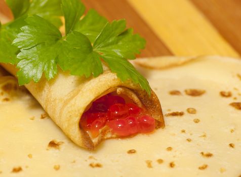 Pancake with red caviar and celery close up