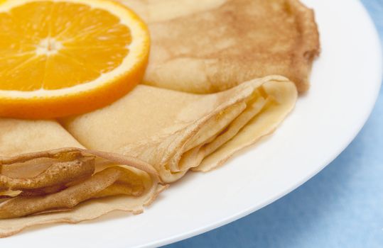 Pancakes with orange on a white plate






Pancakes with orange, shaving chocolate and red currants close up