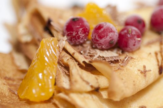 Pancakes with orange, shaving chocolate and red currants close up