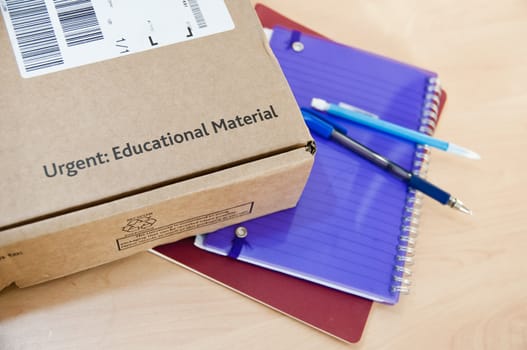 High angle shot of distance learning cardboard box with notebooks underneath.