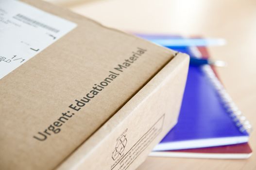 High angle shot of distance learning cardboard box with notebooks underneath.