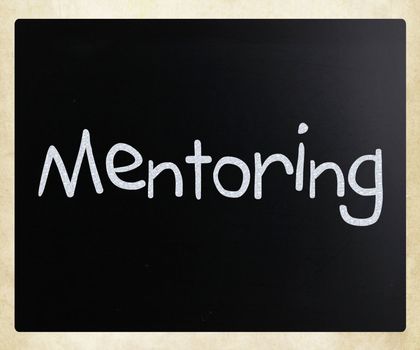 The word "Mentoring" handwritten with white chalk on a blackboard