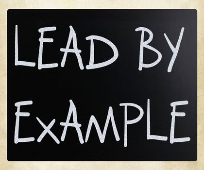 "Lead by example" handwritten with white chalk on a blackboard