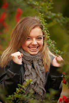 Beautiful positive girl in the bushes Viburnum. Very big smile and raised his hands happily