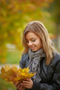 Beautiful girl in the autumn park collects leaves