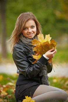 Beautiful girl in the autumn park collects leaves