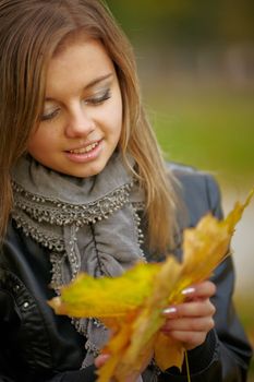 Beautiful girl in the autumn park collects leaves