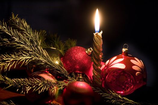 Candle and christmas-tree decorations on a black background
