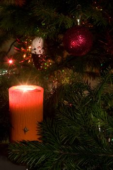 Candle and christmas-tree decorations on a black background