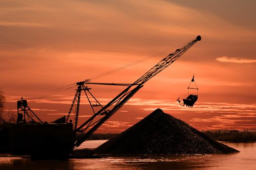 Silhouette of a career dredge on a background of an evening dawn