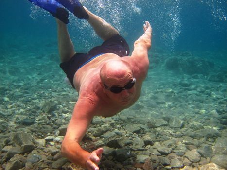 adult man swimming underwater in glasses and flippers