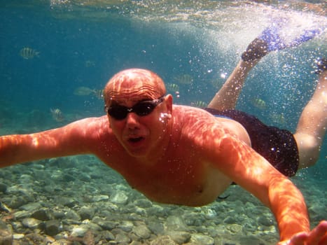 adult man swimming underwater in glasses and flippers